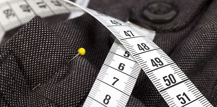 Clothing Alterations: A tape measure draped over a piece of patterned fabric.